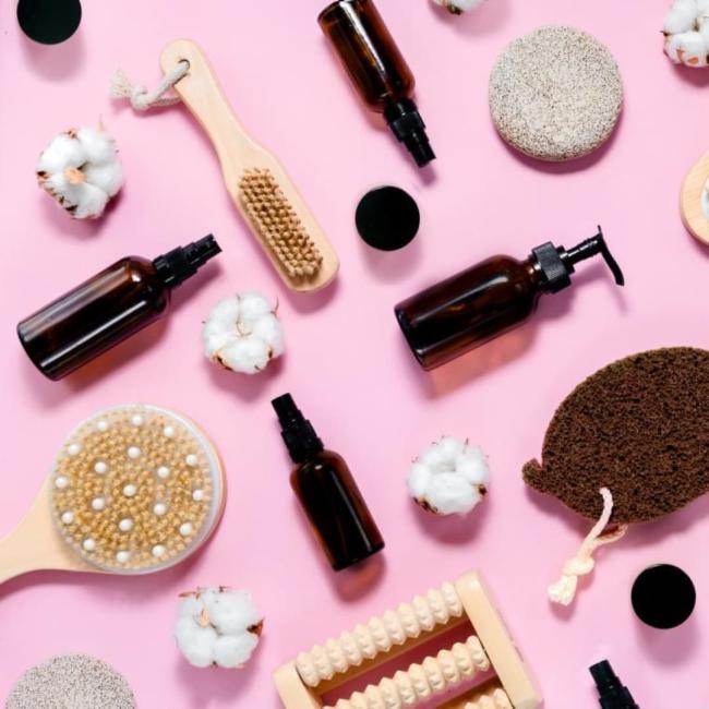 A selection of body and skin care products on a pink surface