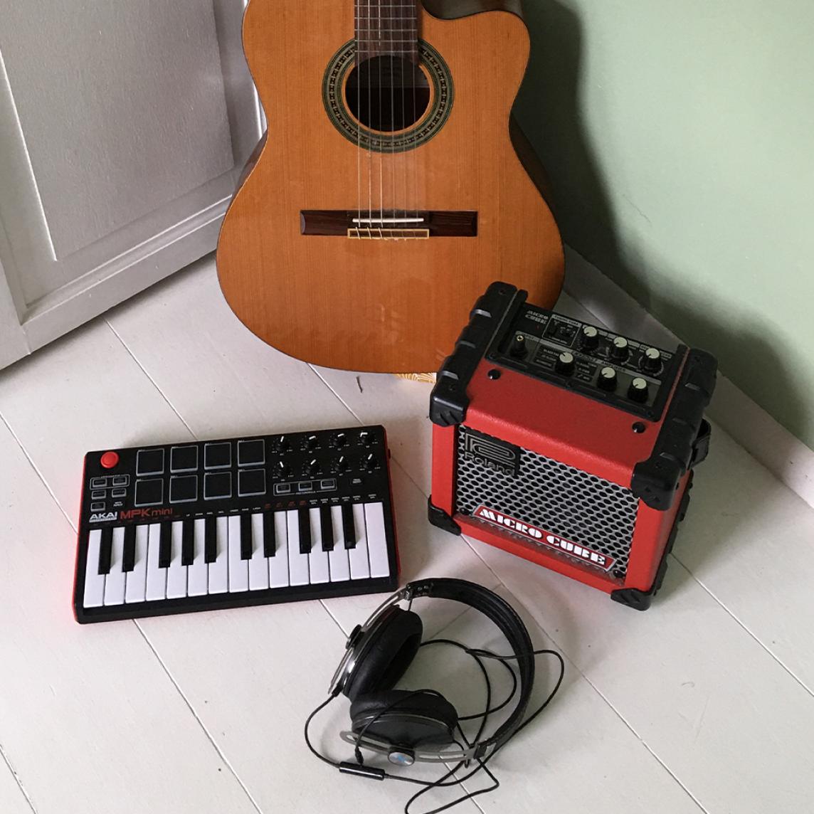 A synthesizer, guitar and guitar amp on a white floor