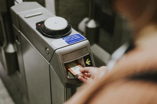 An image of a person inserting their train ticket into the barrier