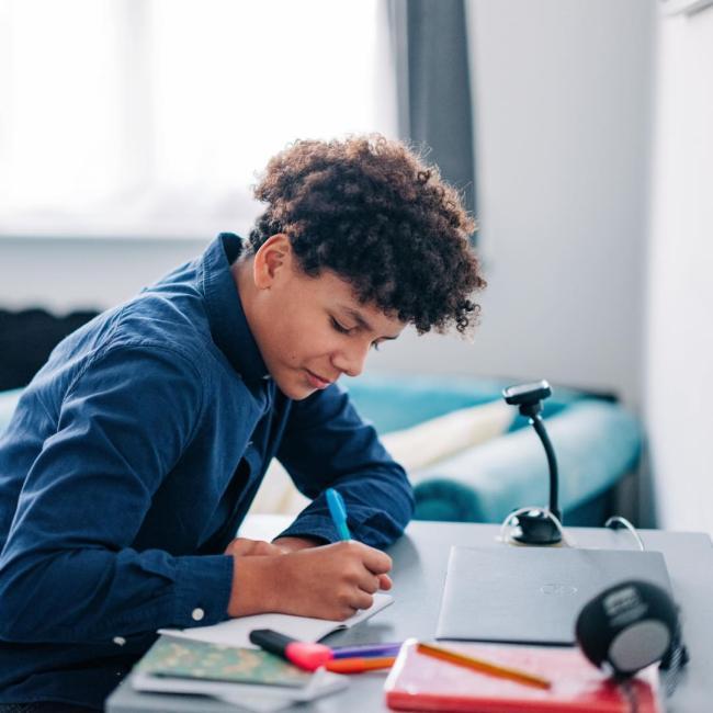 A teenage boy sat at a desk completing school work