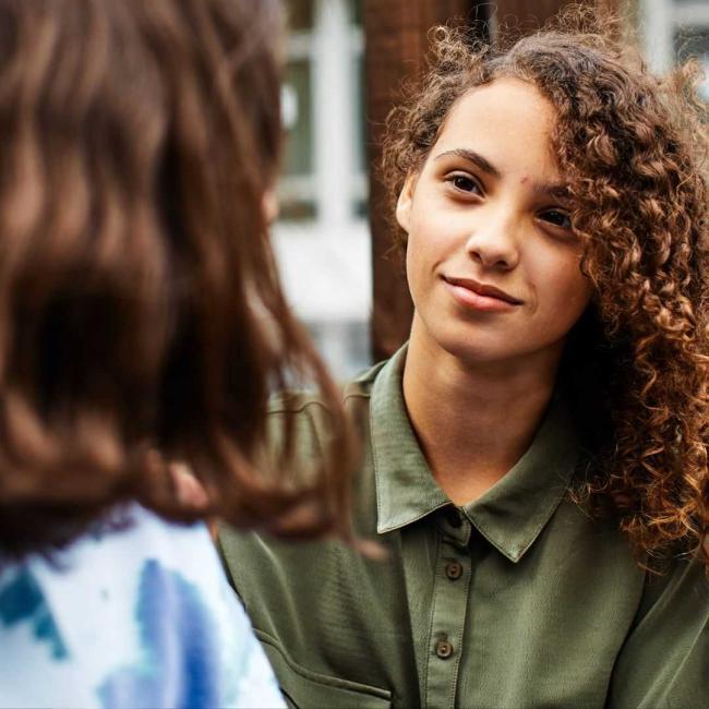 A teenage girl is talking to her therapist outdoors.