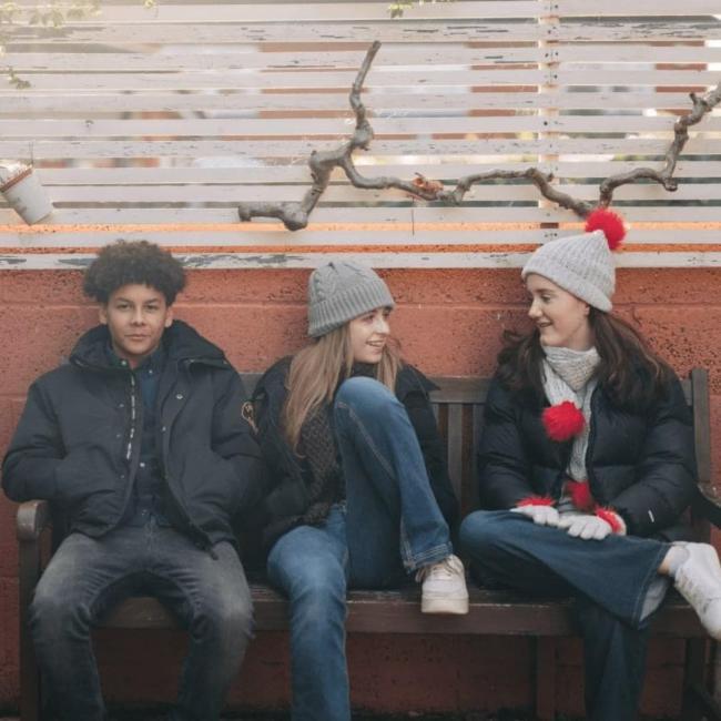 Three teenagers relaxing on a park bench