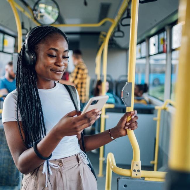 A young women is listening to music and travelling on a bus