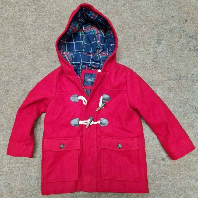 A red childs jacket laid out on the floor.