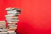 A tall stack of books against a red background