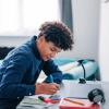 A teenage boy sat at a desk completing school work