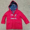A red childs jacket laid out on the floor.