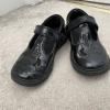 Black patent children's school shoes on a beige carpet.